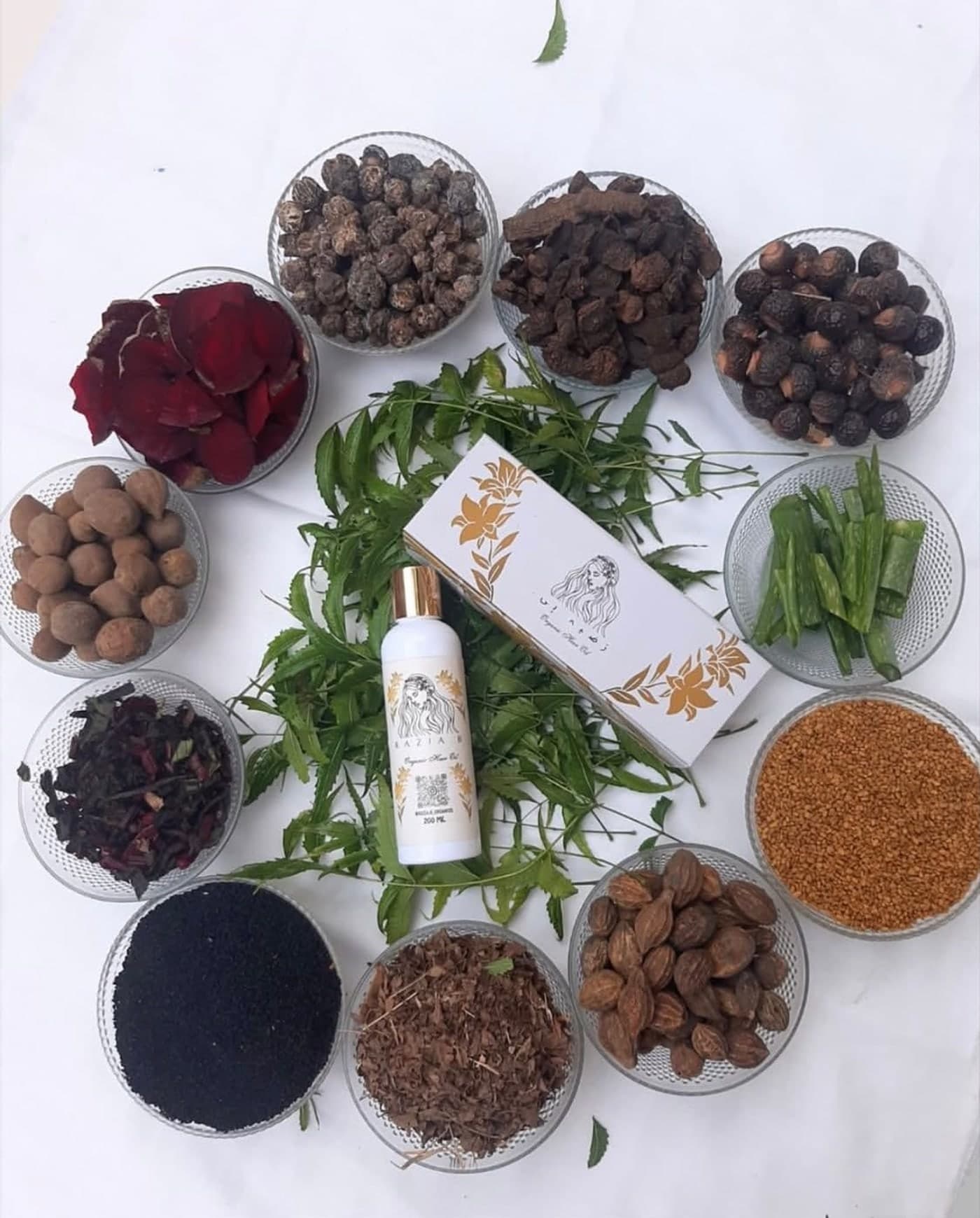 Razia B. Organic Hair Oil with its botanical ingredients laid out around the bottle